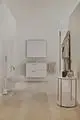 Minimalistisches Badezimmer mit hellen Holzfußboden, weißem WC, schwebendem Waschbecken mit idealer Armatur, Spiegel und Dekoration auf einem runden Beistelltisch. Ideal Standard präsentiert modernes Design.
